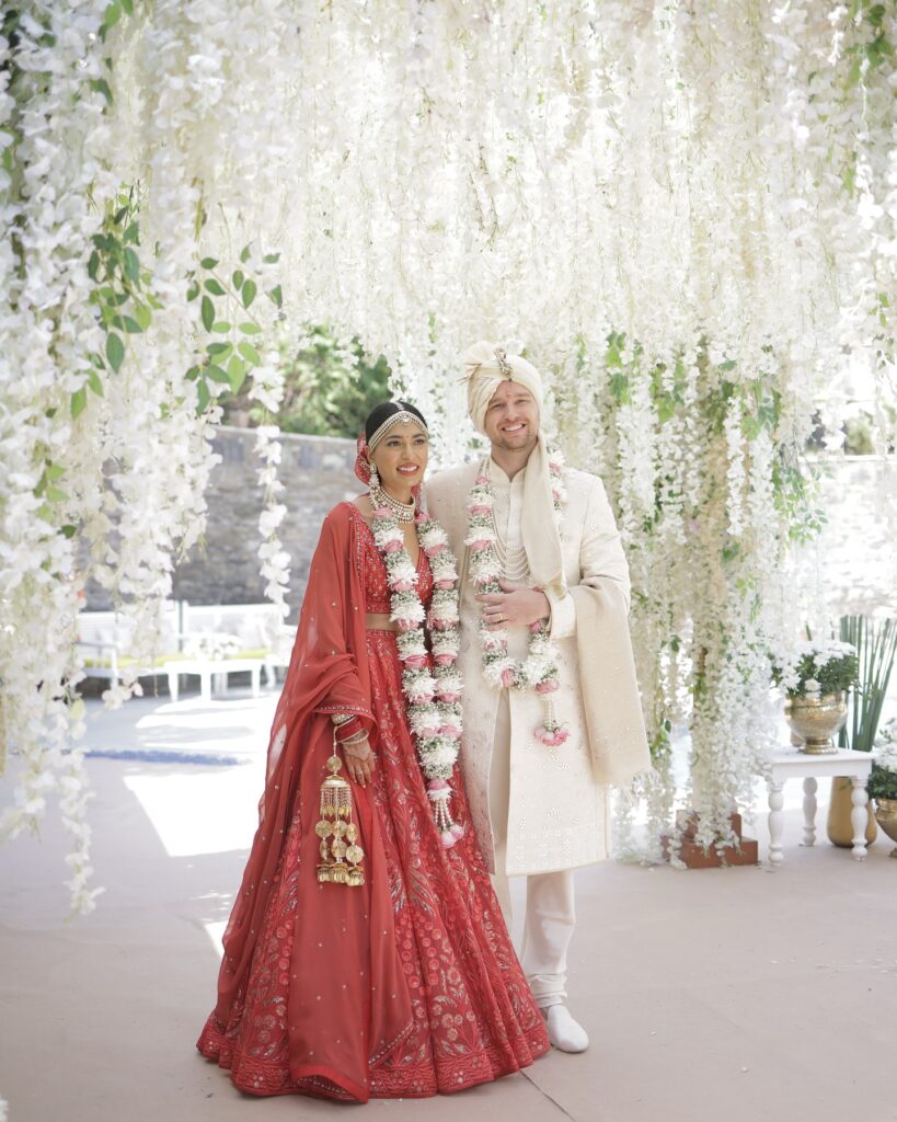 Bride and groom beneath a white floral wedding installation